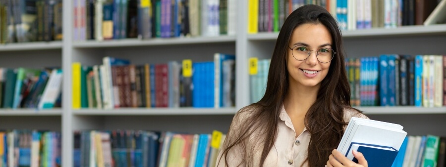 livros para concursos: mulher sorrindo em biblioteca